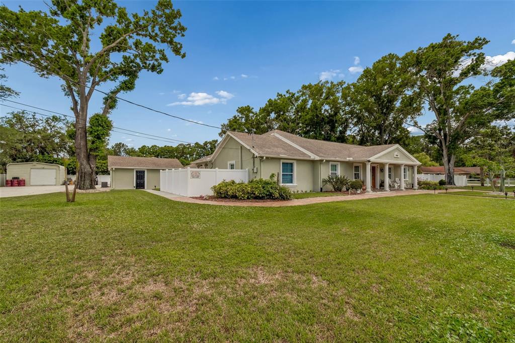 A light green single-story house with a white fence and a detached garage — 9406 W FLORA STREET, TAMPA, FL
