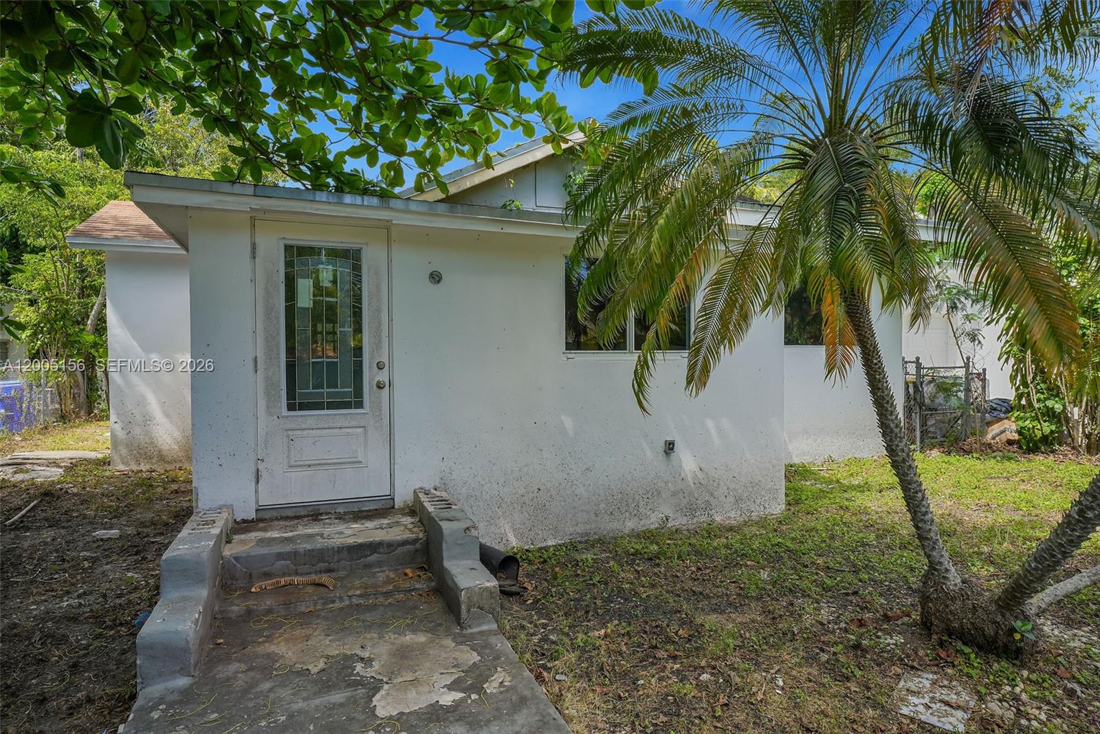 The exterior of a small, white house features a front door and a palm tree — 3637 Frow Ave, Miami FL 33133, MIAMI, FL
