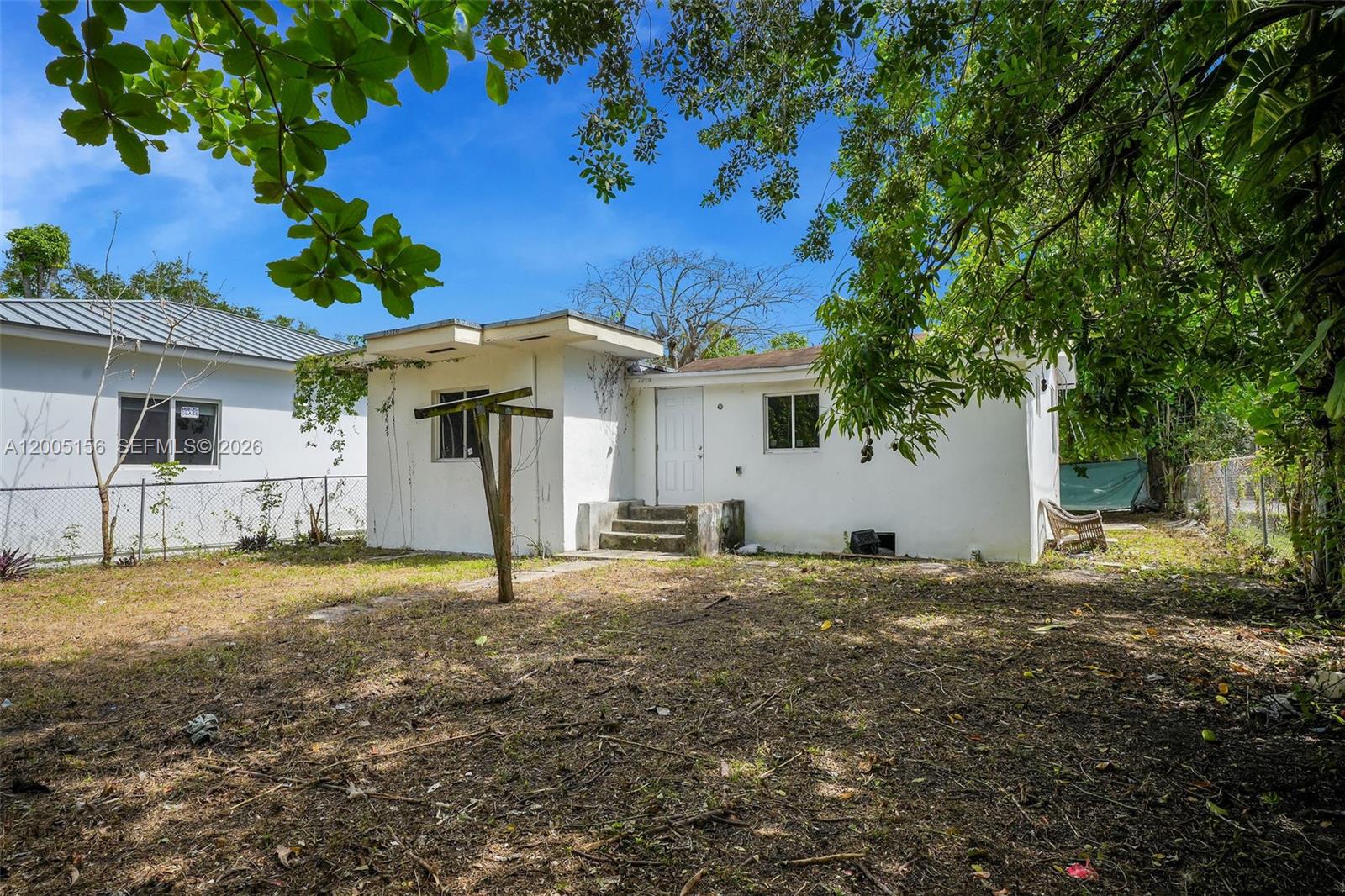 A white, single-story house exterior features a small porch, a wooden post, and yard space — 3637 Frow Ave, Miami FL 33133, MIAMI, FL