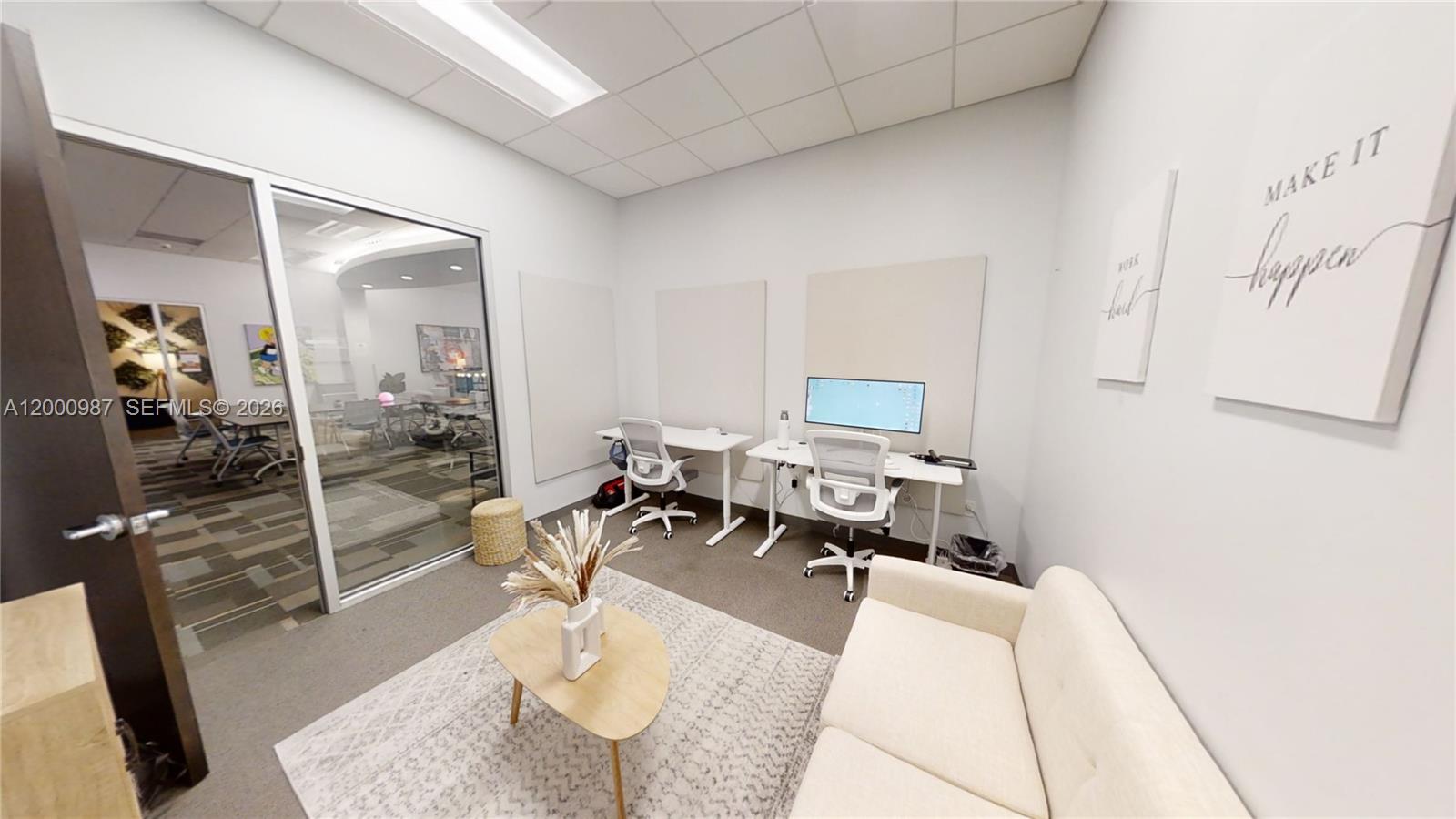 An office space features two desks, white chairs, a small sofa, and a glass wall — 1501 Biscayne Blvd # D, FL 33132, FL