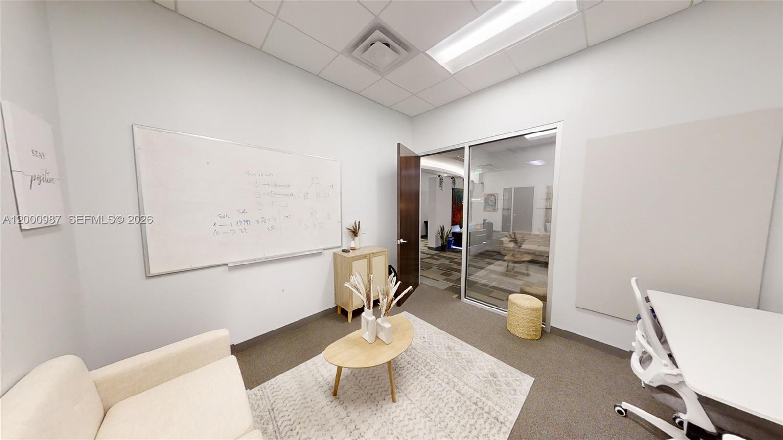 A small office features a whiteboard, a sofa, a coffee table, and a glass door — 1501 Biscayne Blvd # D, FL 33132, FL