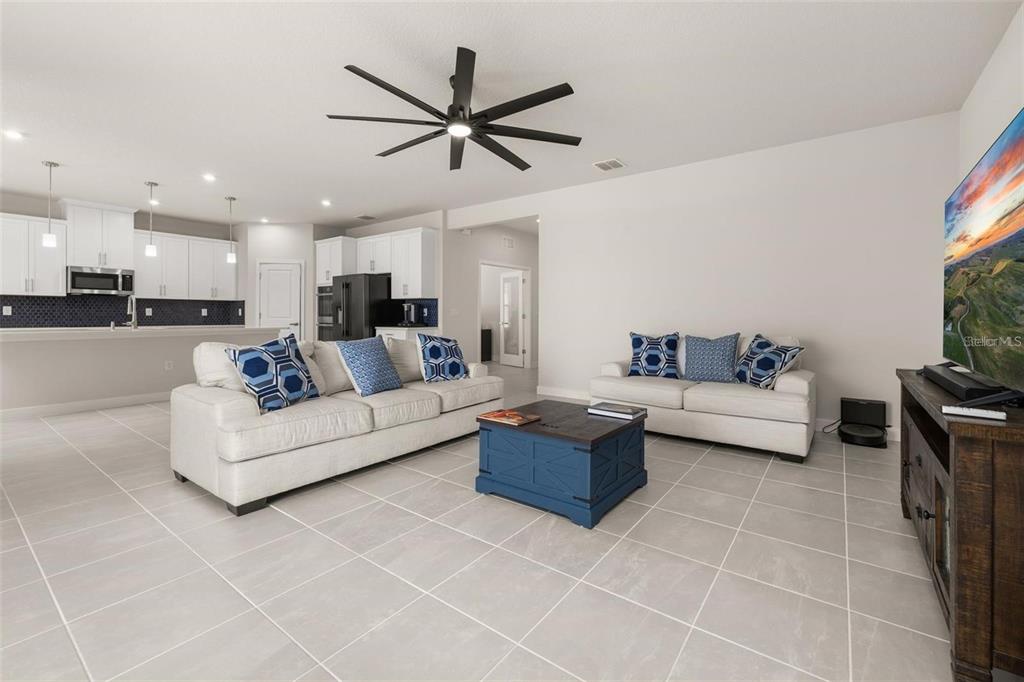 A living room with white sofas, a blue coffee table, and an open-concept kitchen — 11182 NELLIE CROSSING CIRCLE, CLERMONT, FL