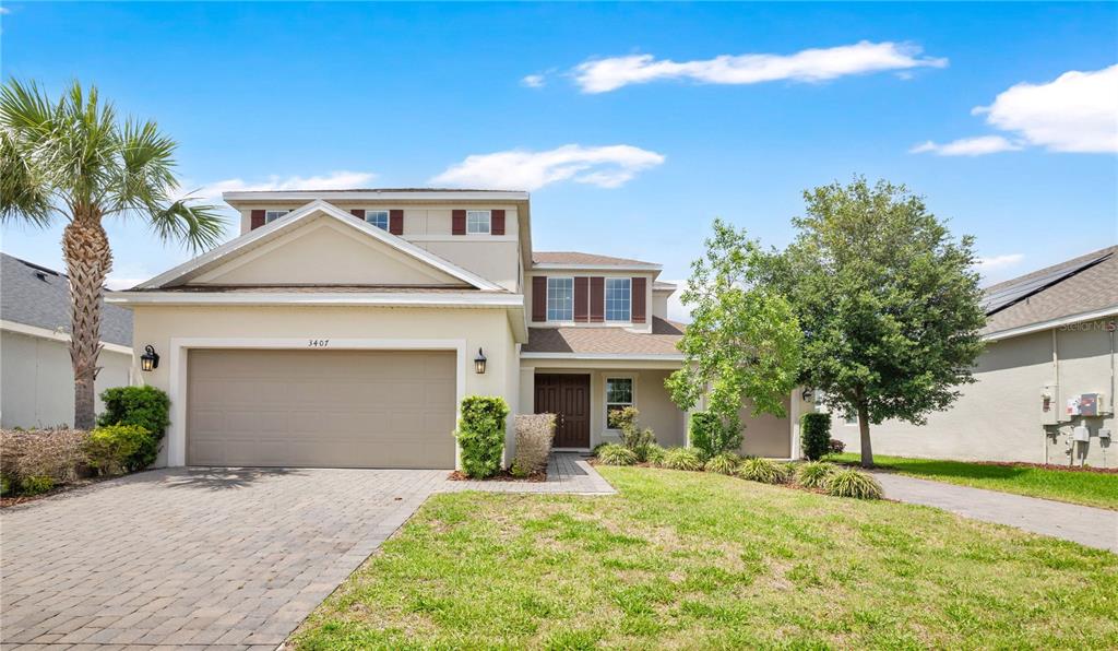 A two-story suburban house with a beige stucco exterior, a two-car garage, and a driveway — 3407 CURRENT AVENUE, WINTER GARDEN, FL