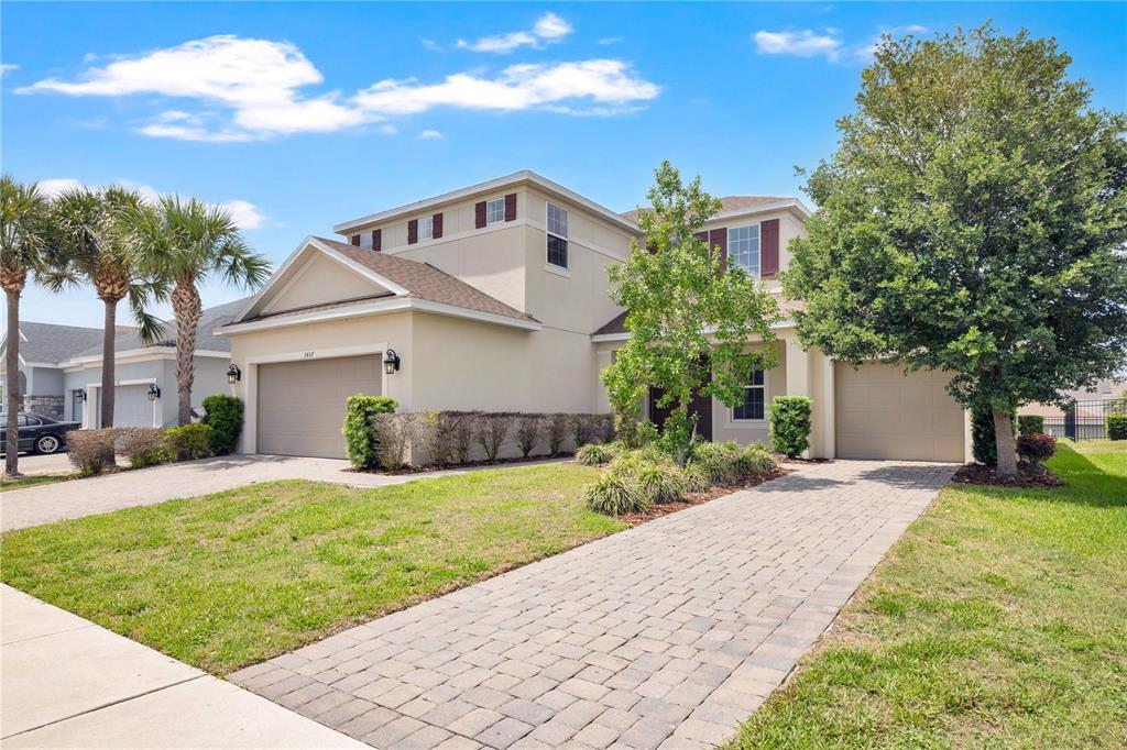 A two-story house with a beige stucco exterior, two garages, and a paved driveway — 3407 CURRENT AVENUE, WINTER GARDEN, FL