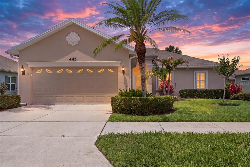 A single-story house with a beige stucco exterior, a two-car garage, and a palm tree — 445 TOMOKA DRIVE, ENGLEWOOD, FL