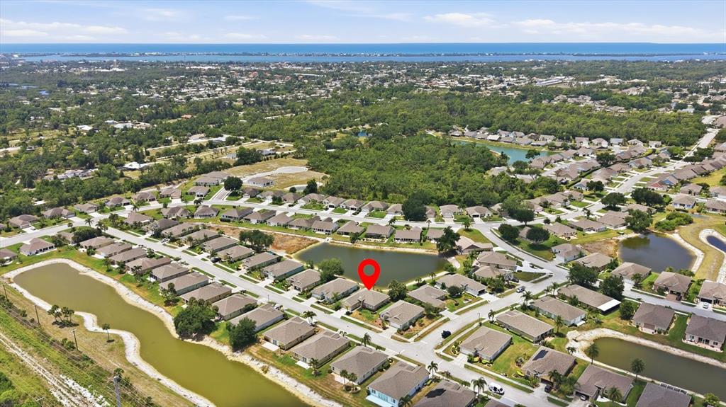 An aerial view shows a suburban neighborhood with houses surrounding several small ponds — 445 TOMOKA DRIVE, ENGLEWOOD, FL