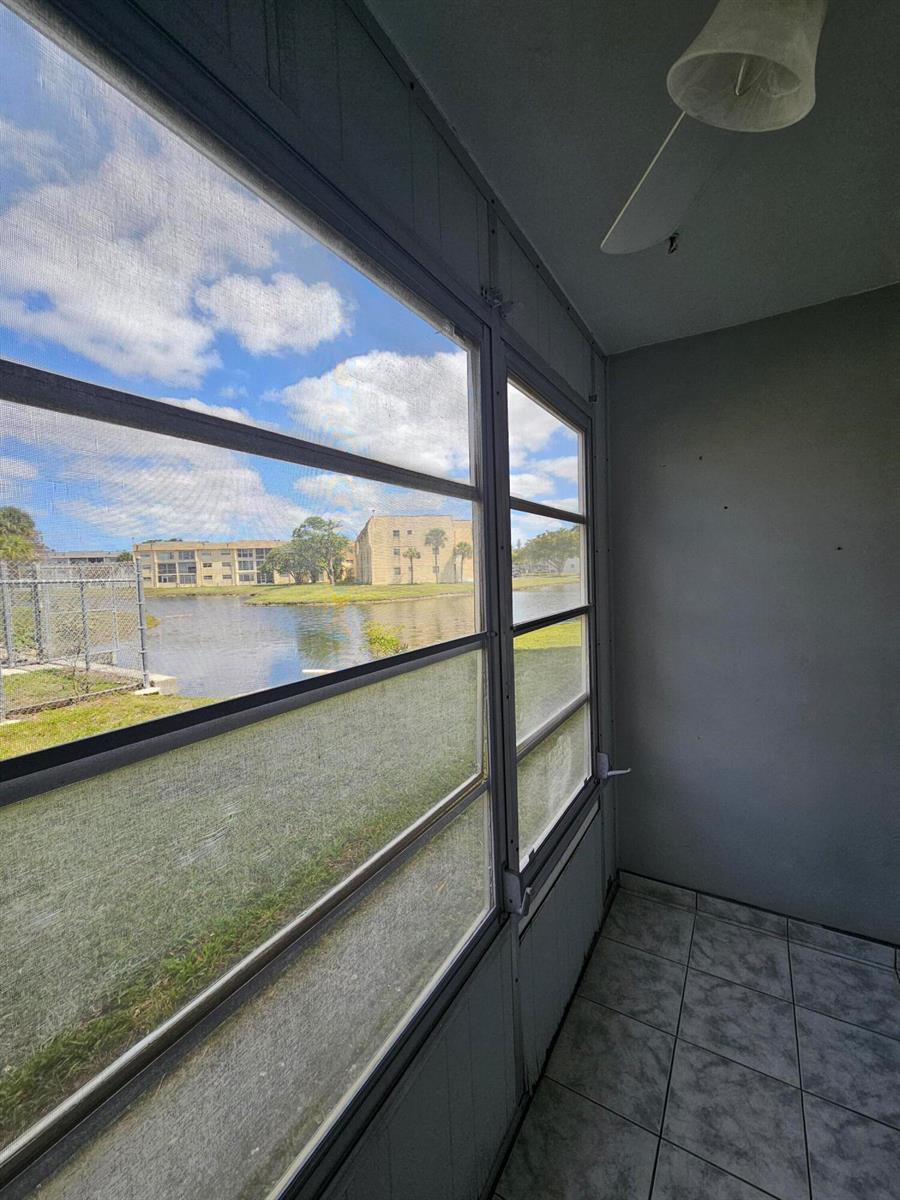 A tiled screened-in porch overlooks a lake and apartment buildings under a cloudy sky — SUNRISE, FL