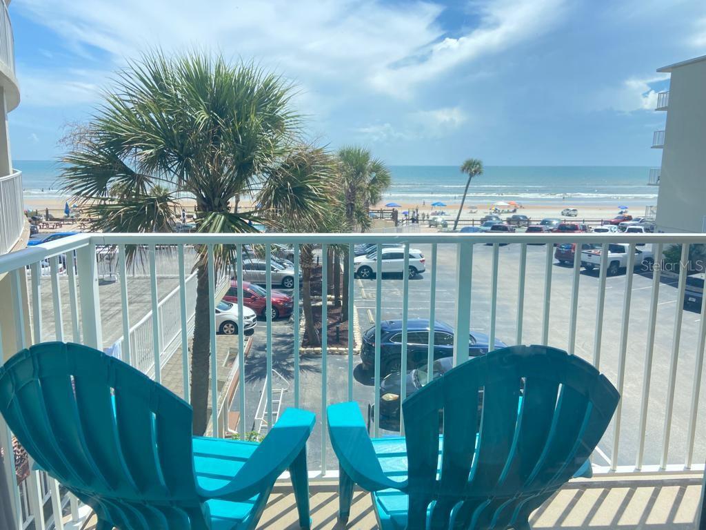 A balcony view overlooking a parking lot, palm trees, and the ocean with two chairs — 1233 S ATLANTIC AVENUE UNIT 3160, DAYTONA BEACH, FL