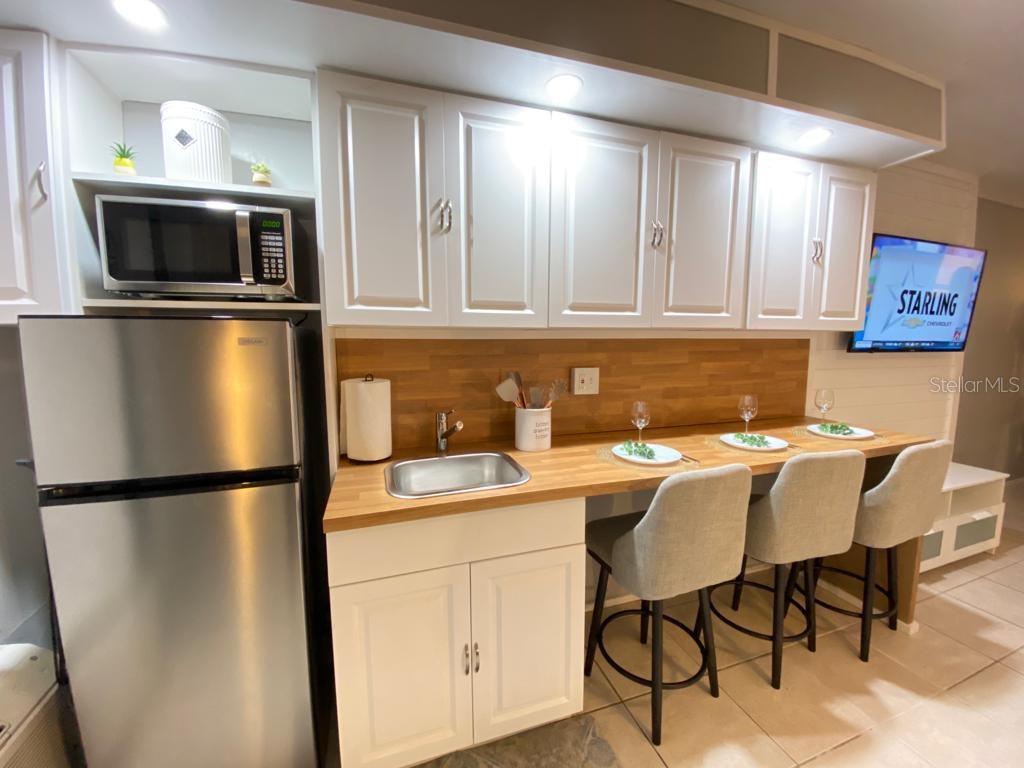 A kitchen area features white cabinets, a stainless steel refrigerator, and a wood countertop island — 1233 S ATLANTIC AVENUE UNIT 3160, DAYTONA BEACH, FL
