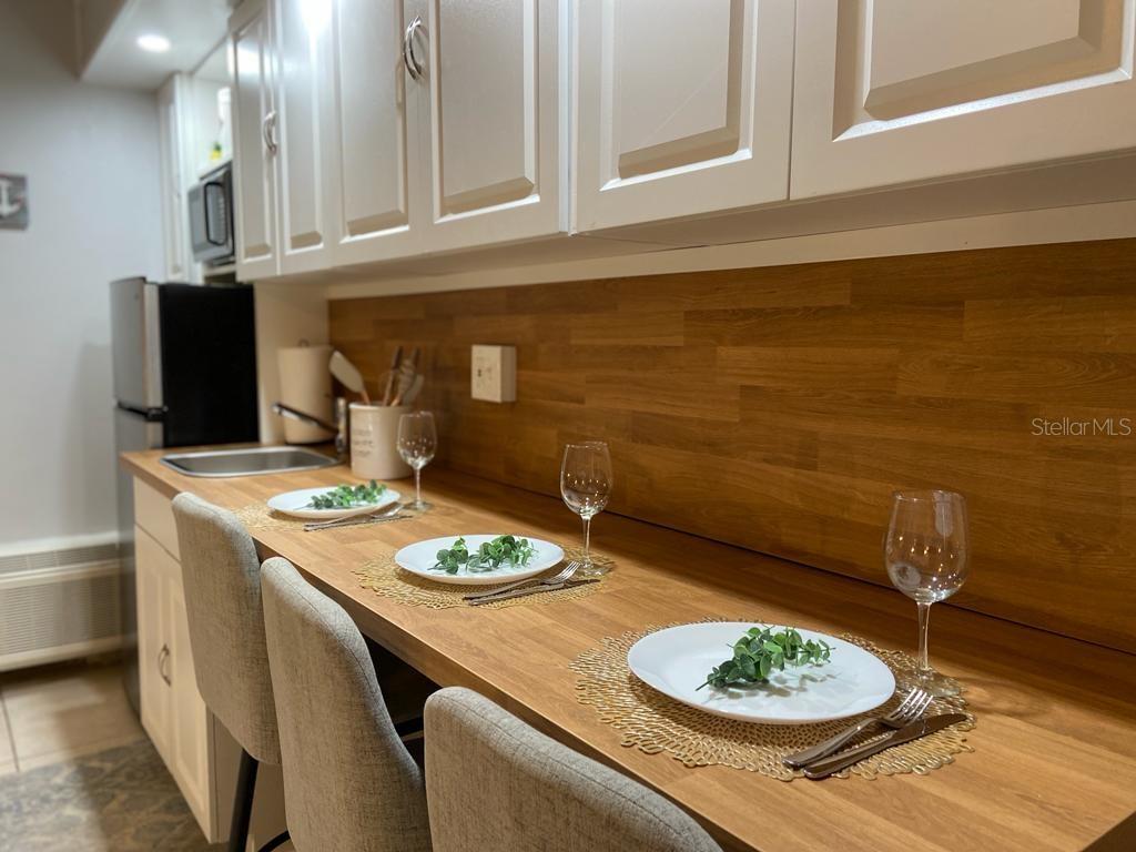 A kitchen features a wooden countertop breakfast bar with three chairs and white cabinets — 1233 S ATLANTIC AVENUE UNIT 3160, DAYTONA BEACH, FL