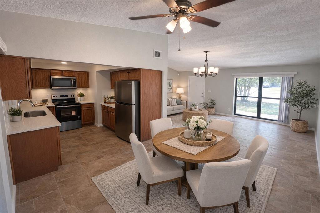 An open-concept kitchen and dining area features wood cabinets, stainless steel appliances, and tile flooring — 3823 PINE RIDGE ROAD, ORLANDO, FL