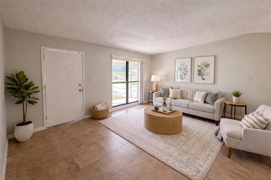 A living room features tile flooring, a beige sofa, a round coffee table, and a door — 3823 PINE RIDGE ROAD, ORLANDO, FL