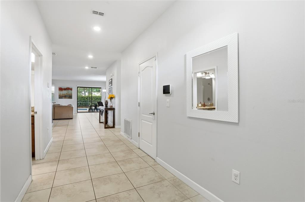A tiled hallway leads to an open living area with a view of a pool — 9039 SHADOW MOUNTAIN STREET, DAVENPORT, FL