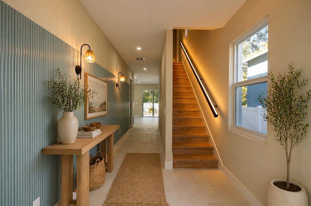 A hallway features a slatted blue accent wall, a wooden console table, and a wooden staircase — 7617 AMHERST STREET, TAMPA, FL