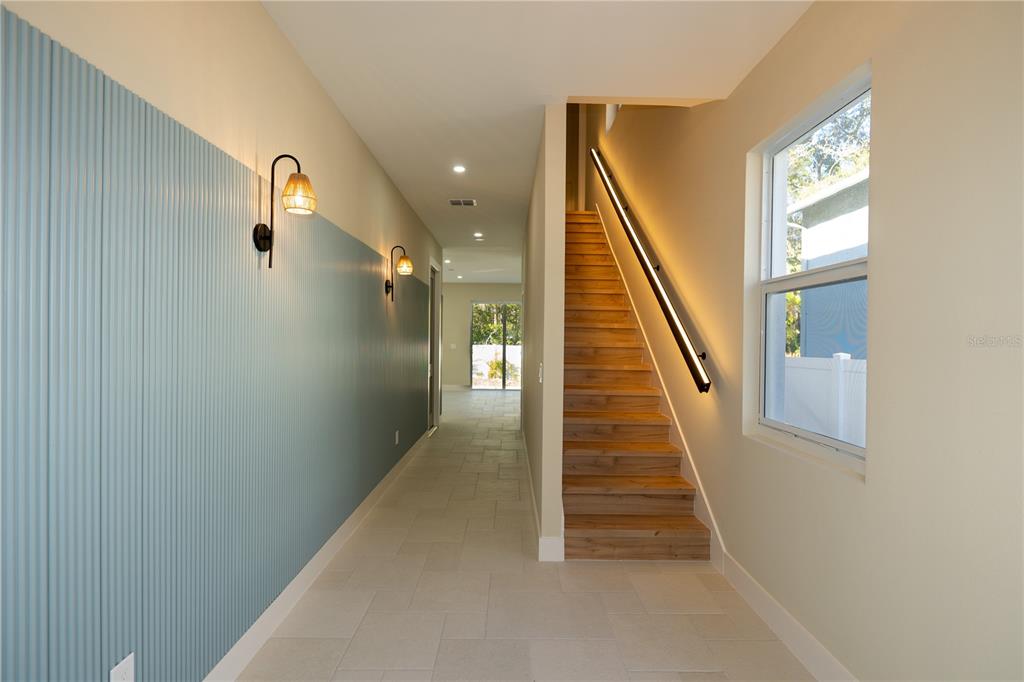 A hallway features a blue paneled wall, light tile flooring, and a wooden staircase — 7617 AMHERST STREET, TAMPA, FL