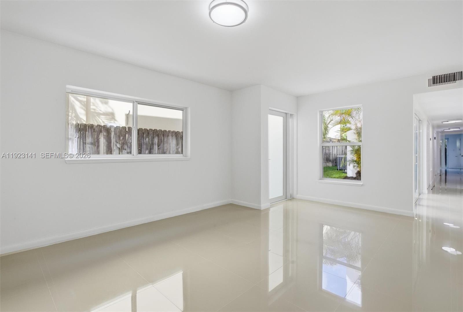 An empty room features white walls, glossy tile flooring, a ceiling light, and two windows — 1045 SW 25th Ave, Miami FL 33135, MIAMI, FL