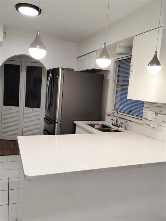 A kitchen features white countertops, stainless steel appliances, and three pendant lights over a peninsula — 708 ANTELOPE WAY, KISSIMMEE, FL
