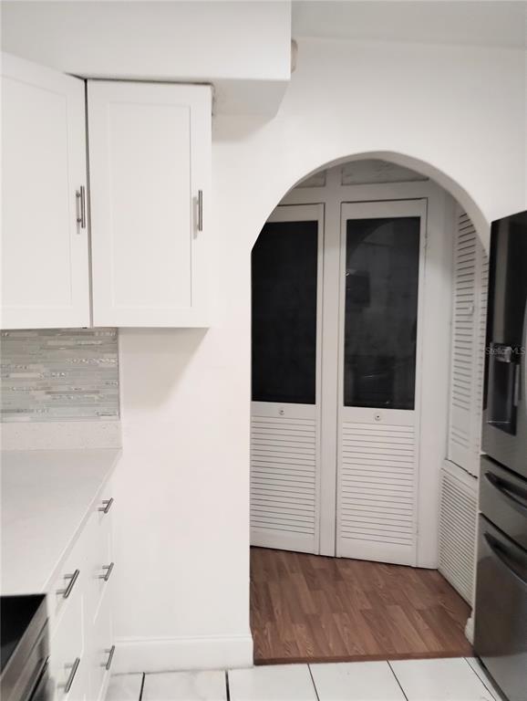 A kitchen features white cabinets, a tiled backsplash, and an arched doorway leading to a pantry — 708 ANTELOPE WAY, KISSIMMEE, FL
