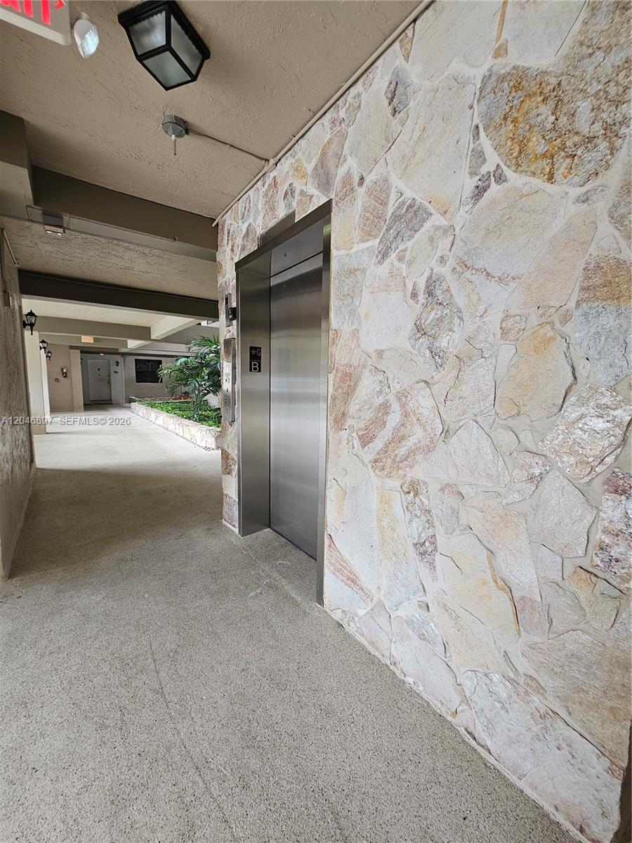 A stainless steel elevator door is set into a wall featuring natural stone cladding — 461 Ives Dairy Rd # 2, Miami FL 33179, MIAMI, FL