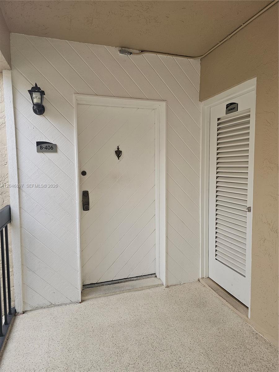 An exterior view shows a white front door labeled B-406 next to a laundry closet — 461 Ives Dairy Rd # 2, Miami FL 33179, MIAMI, FL