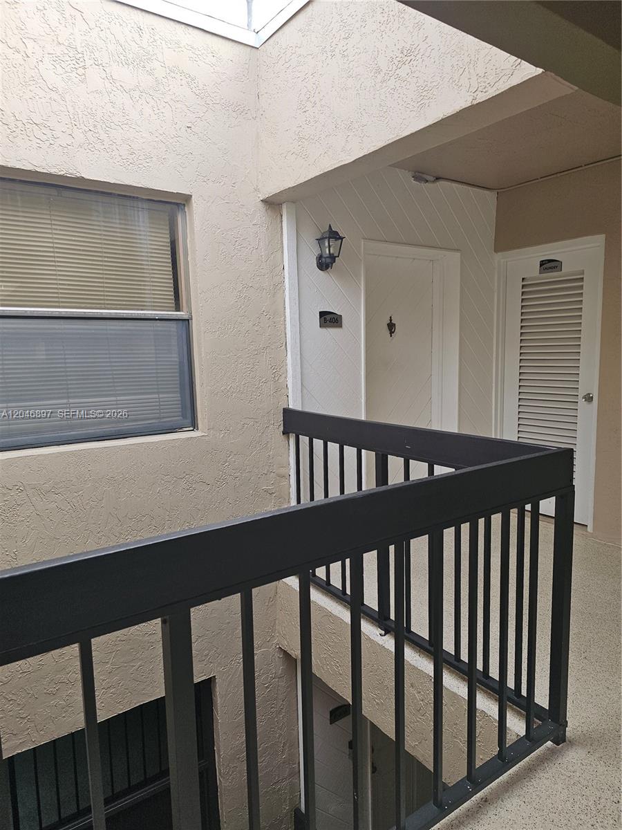 An exterior view of a building corridor featuring a unit door, a laundry closet, and railing — 461 Ives Dairy Rd # 2, Miami FL 33179, MIAMI, FL