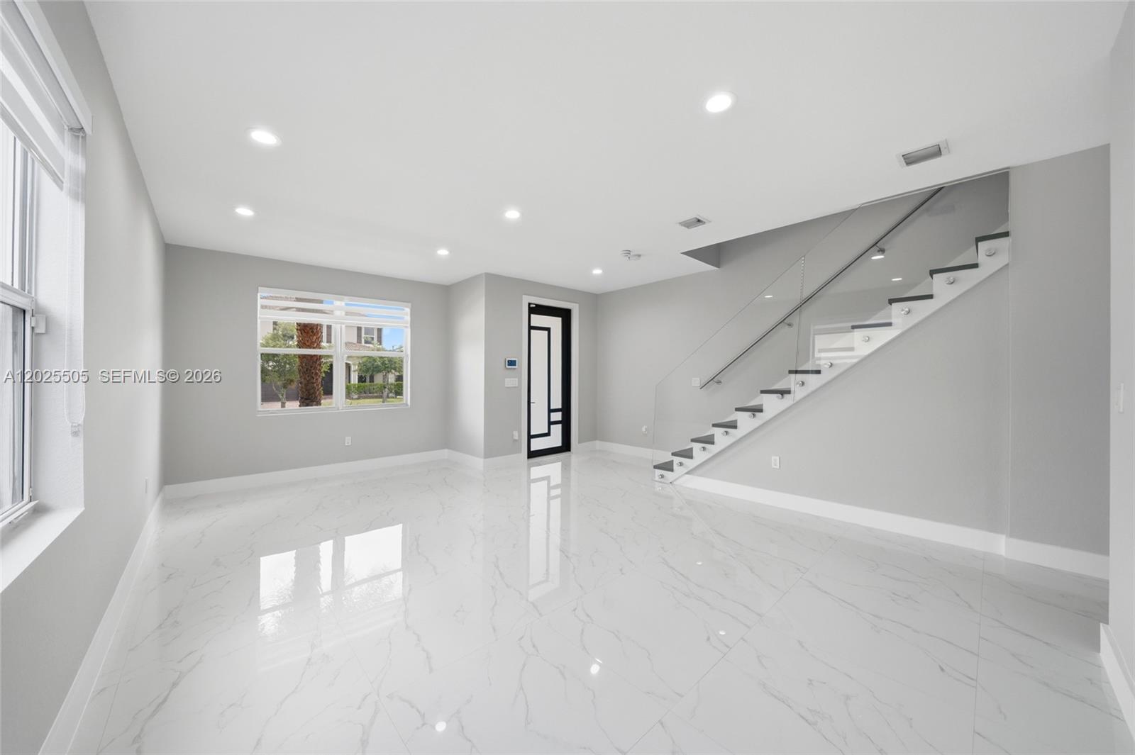 A modern living room features white marble floors, gray walls, and a glass-railed staircase — 4107 NE 20th St, Homestead FL 33033, HOMESTEAD, FL