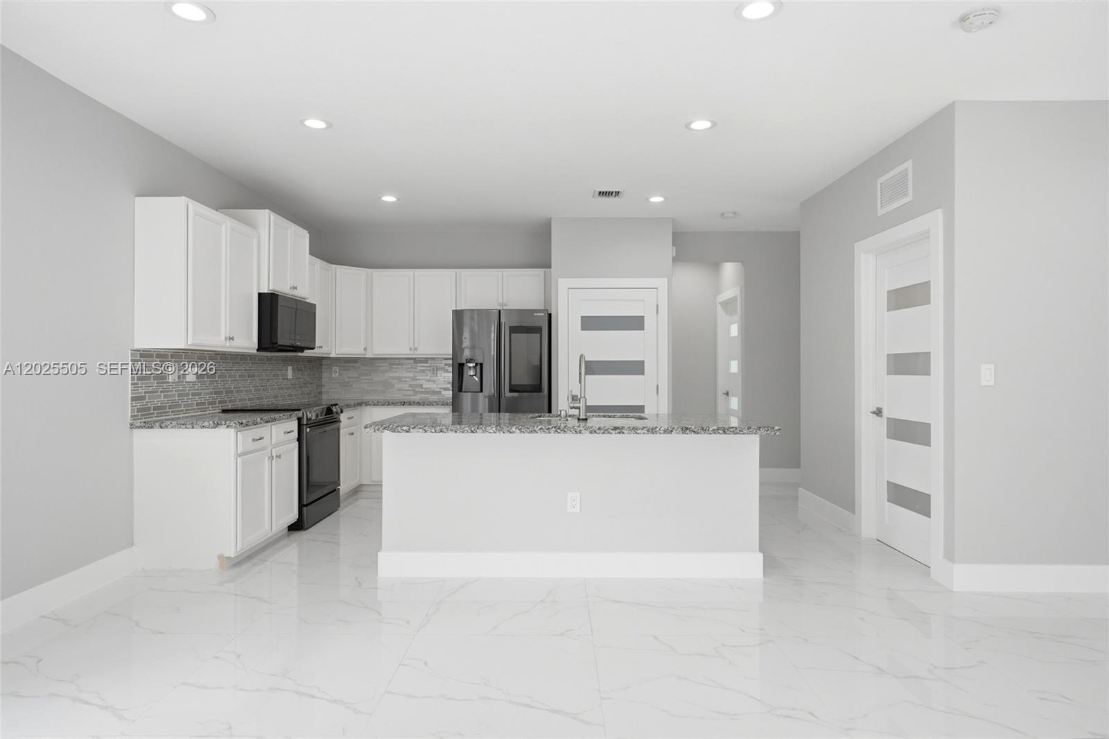 A modern kitchen features white cabinets, granite countertops, stainless steel appliances, and white tile flooring — 4107 NE 20th St, Homestead FL 33033, HOMESTEAD, FL