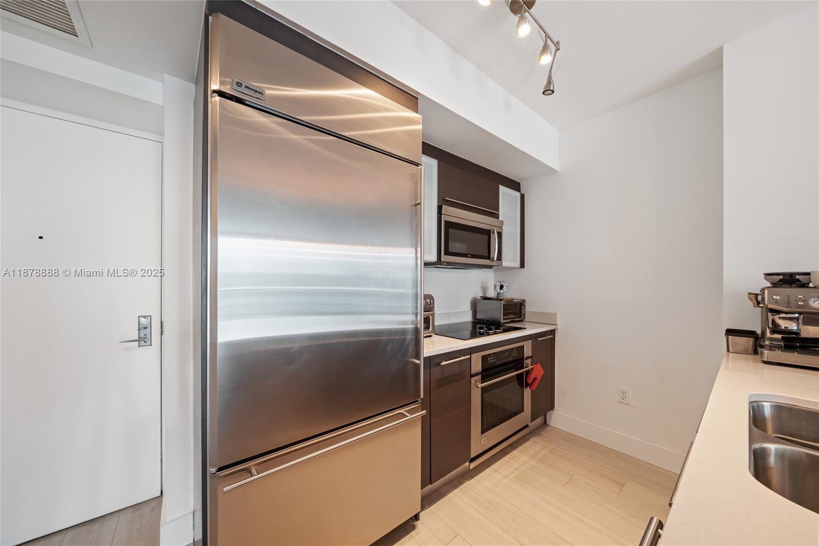 A modern kitchen and dining area feature dark cabinetry, a glass table, and gold accents — 55 SE 6th St # 1908, Miami FL 33131, MIAMI, FL