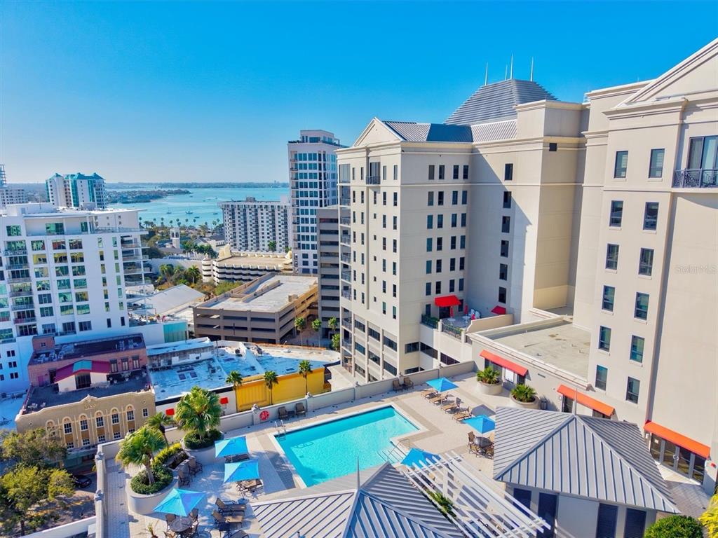 An elevated view of a hotel rooftop pool deck overlooking a city and a bay — 50 CENTRAL AVENUE UNIT 15A, SARASOTA, FL