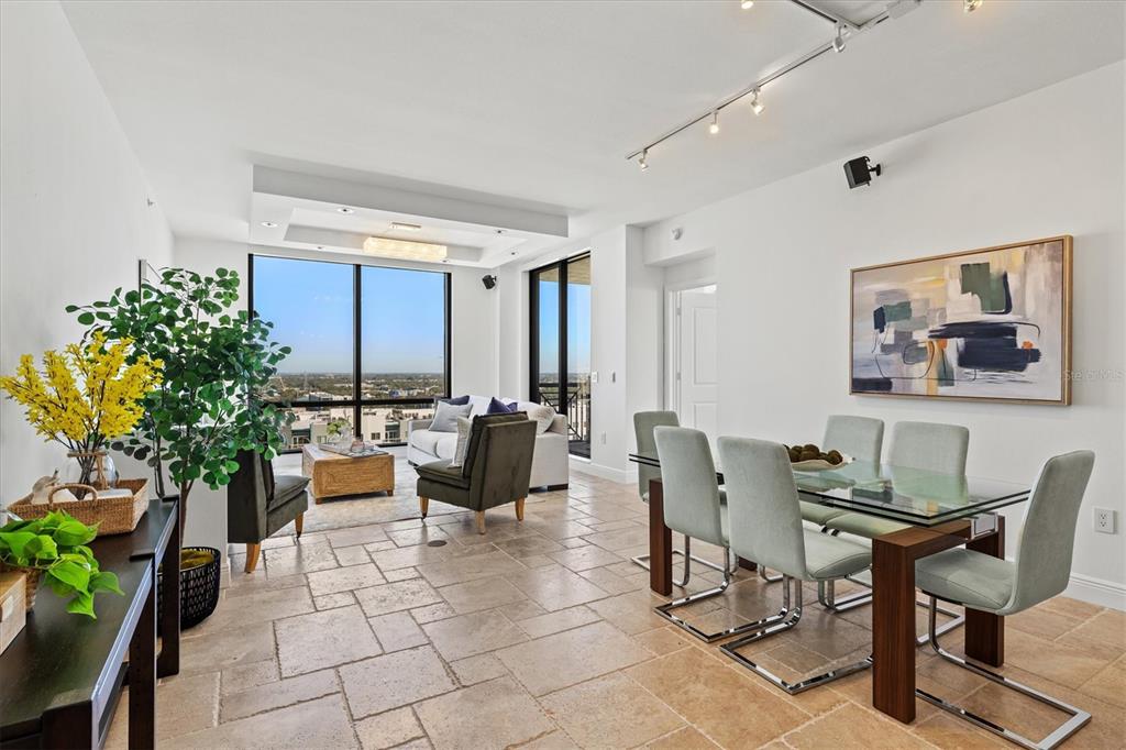 A bright open-concept living and dining area features tile flooring, floor-to-ceiling windows, and city views — 50 CENTRAL AVENUE UNIT 15A, SARASOTA, FL