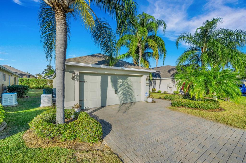 A paved driveway leads to a two-car garage of a single-story home with palm trees — 536 ARENA DRIVE, DAVENPORT, FL