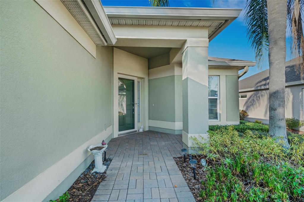 A paved walkway leads to the covered front entryway of a light green stucco house — 536 ARENA DRIVE, DAVENPORT, FL