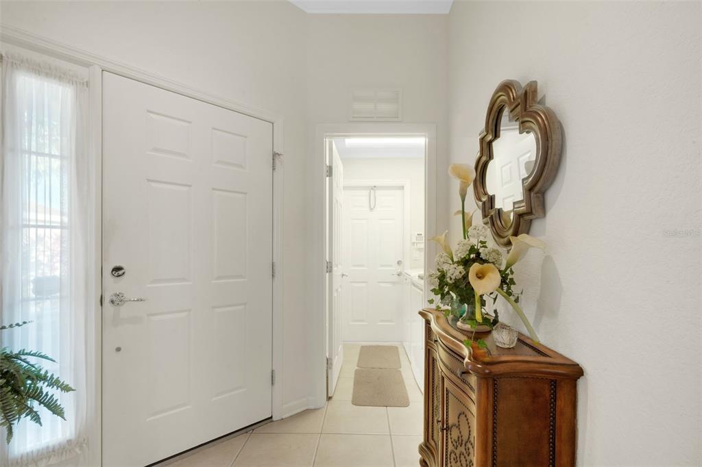 An entryway features a white door, tile flooring, a wooden cabinet, and a wall mirror — 536 ARENA DRIVE, DAVENPORT, FL