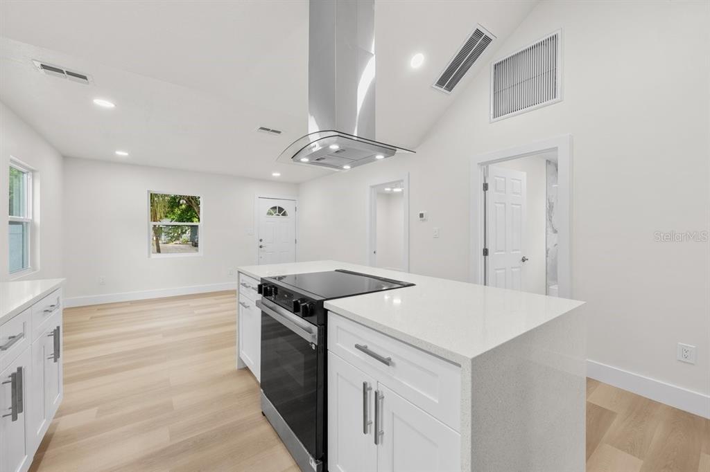 A bright kitchen features white cabinets, a quartz island, and a stainless steel range hood — 2590 18TH AVENUE N, ST PETERSBURG, FL