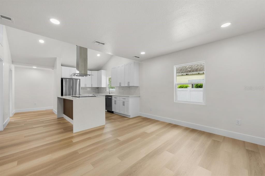 A modern kitchen with white cabinets, a central island, and light wood flooring — 2590 18TH AVENUE N, ST PETERSBURG, FL