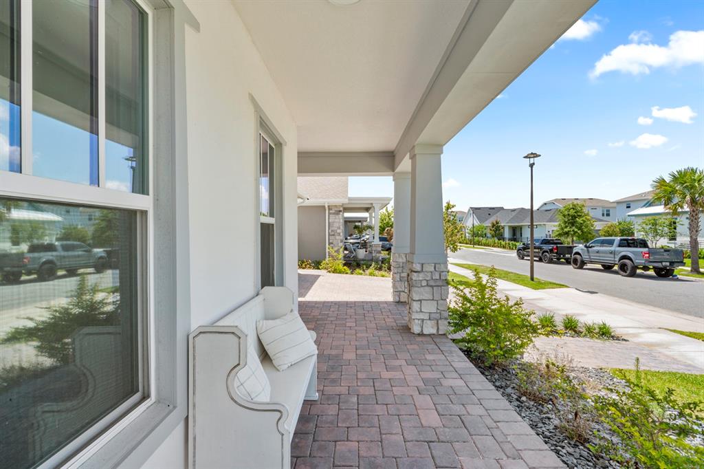 A covered front porch features stone-based columns, a brick paver floor, and a white bench — 13301 MCMILLAN DRIVE, ORLANDO, FL
