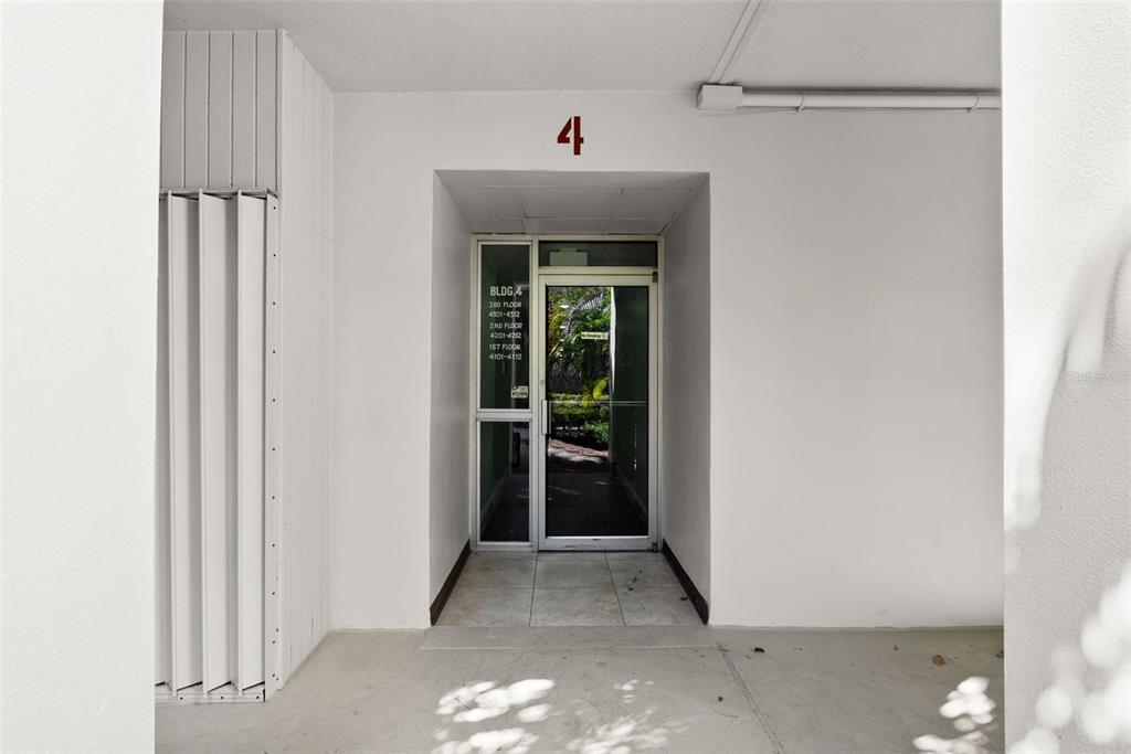 The exterior entrance to a residential building features a glass door and unit numbers — 2700 BAYSHORE BOULEVARD UNIT 4106, DUNEDIN, FL