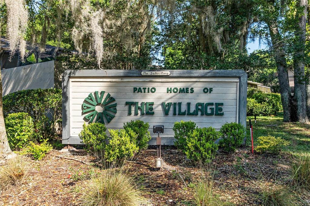 A sign for Patio Homes of The Village stands in a landscaped outdoor area — 3867 NE 17TH STREET CIRCLE, OCALA, FL