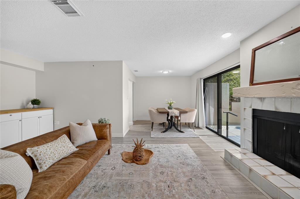 A living room with a leather sofa, fireplace, and dining area featuring sliding glass doors — 3867 NE 17TH STREET CIRCLE, OCALA, FL