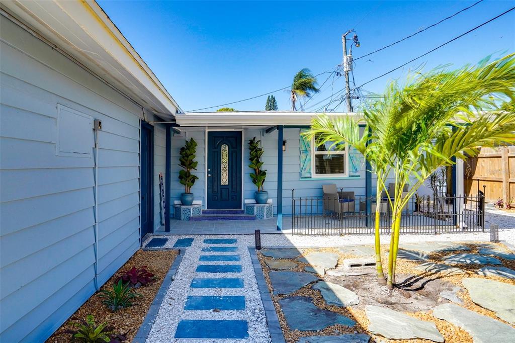 A light blue house exterior features a dark blue front door, stone walkway, and palm tree — 2741 PARMA STREET, SARASOTA, FL