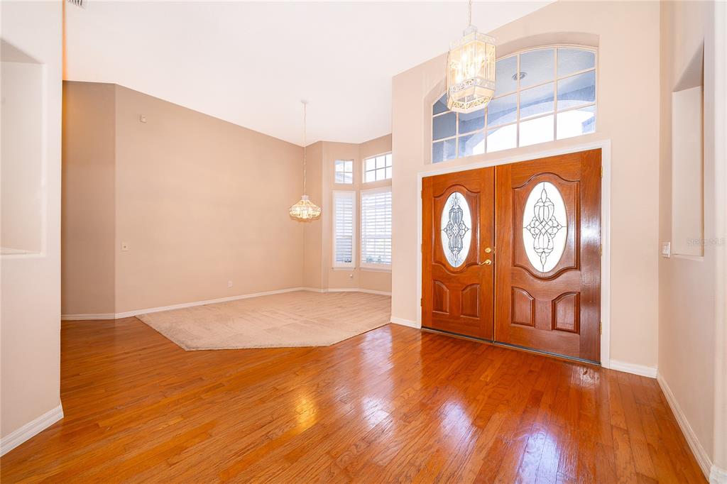 A foyer with hardwood floors leads to a carpeted dining area with a chandelier — 2277 NECTAR WAY, OVIEDO, FL