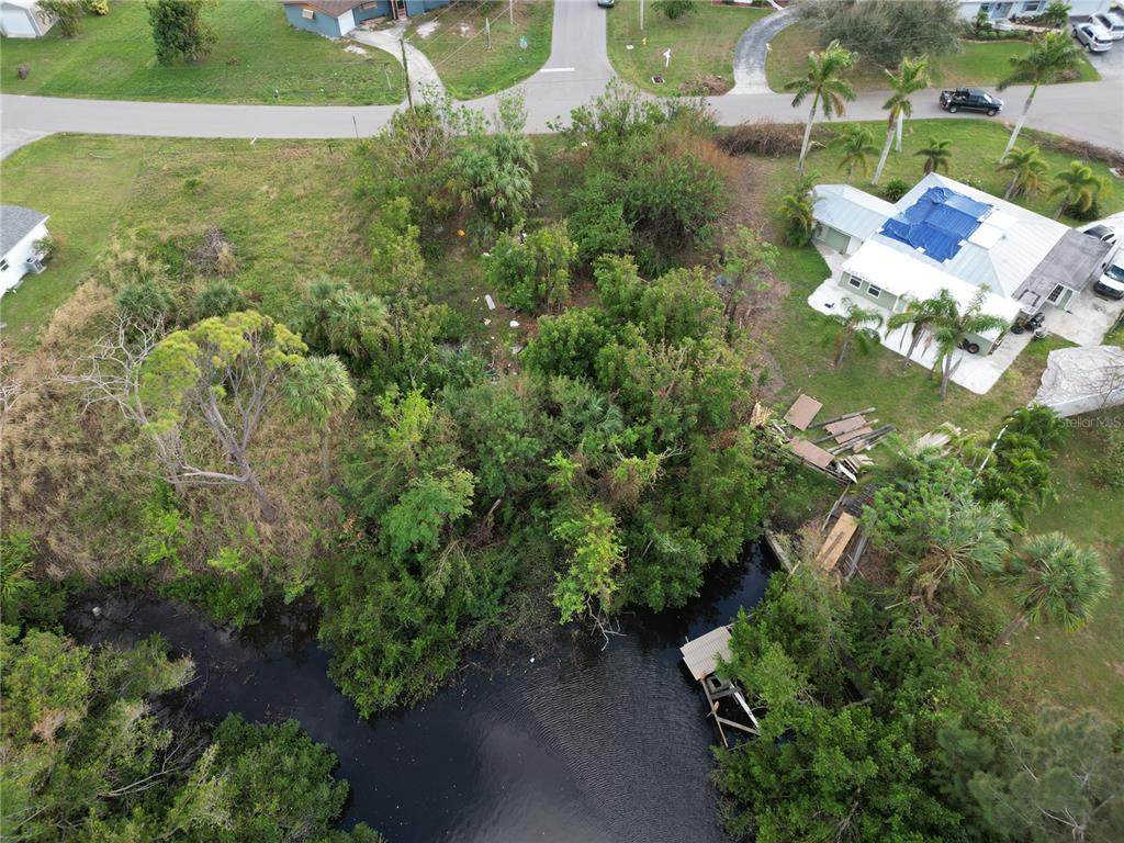 An aerial view shows a wooded residential lot with a small dock on a canal — 108 BARRE DRIVE NW, PORT CHARLOTTE, FL