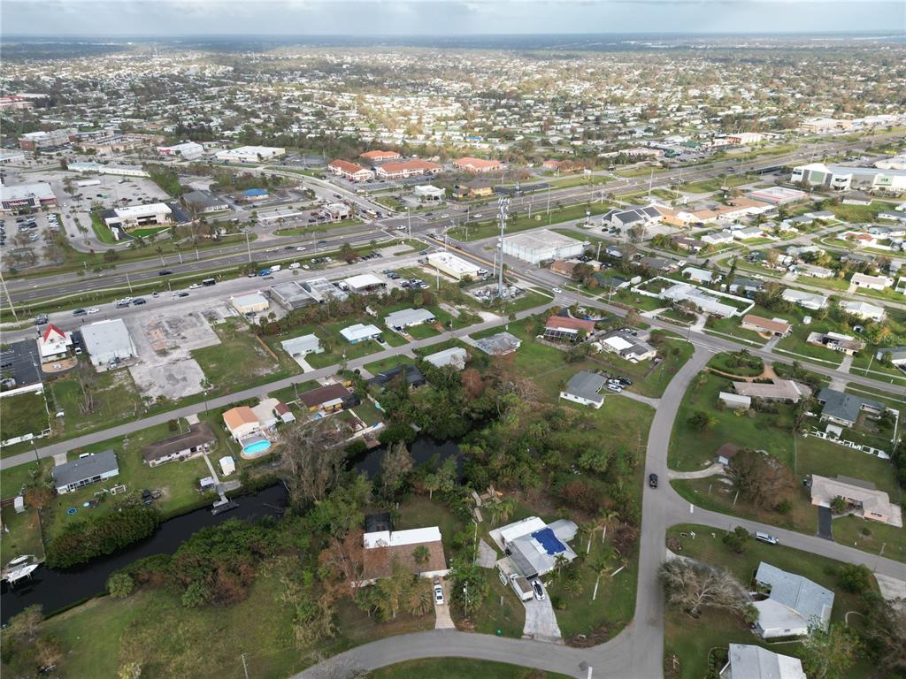 An aerial view shows a residential neighborhood with a canal and a nearby highway — 108 BARRE DRIVE NW, PORT CHARLOTTE, FL