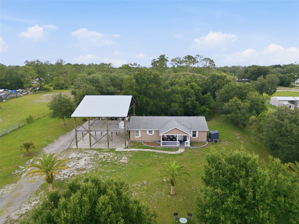 An aerial view shows a house with an attached metal carport on a grassy lot — 32416 PINE ROAD, EUSTIS, FL