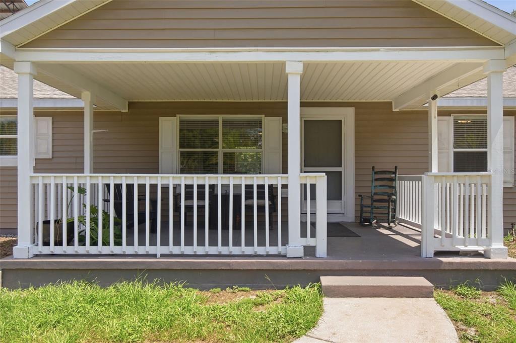 A covered front porch with white railings, a concrete floor, and a rocking chair — 32416 PINE ROAD, EUSTIS, FL