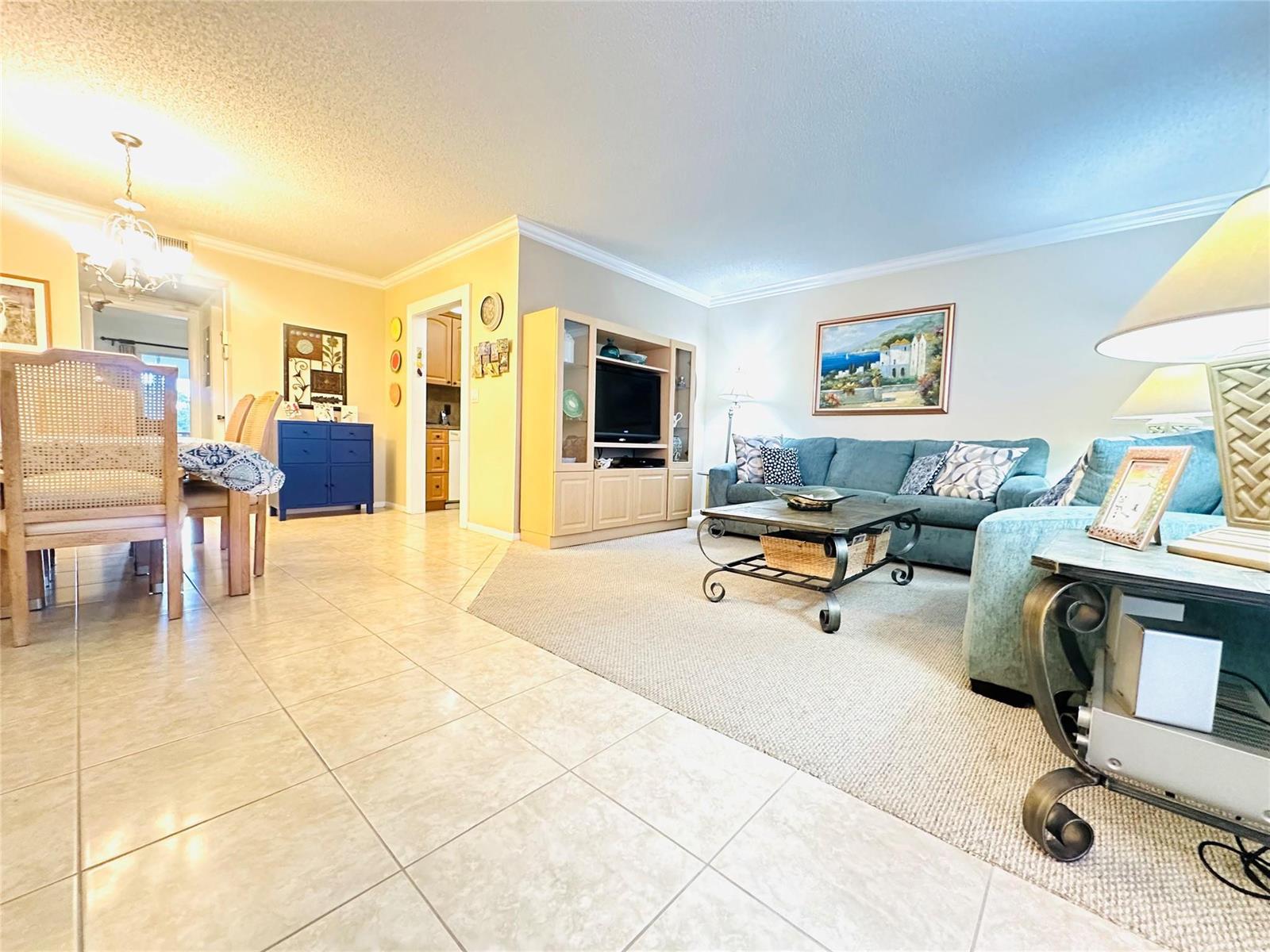A living room and dining area feature tile flooring, a blue sofa, and light walls — 2007 Islewood D # 2007, Deerfield Beach FL 33442, DEERFIELD BEACH, FL