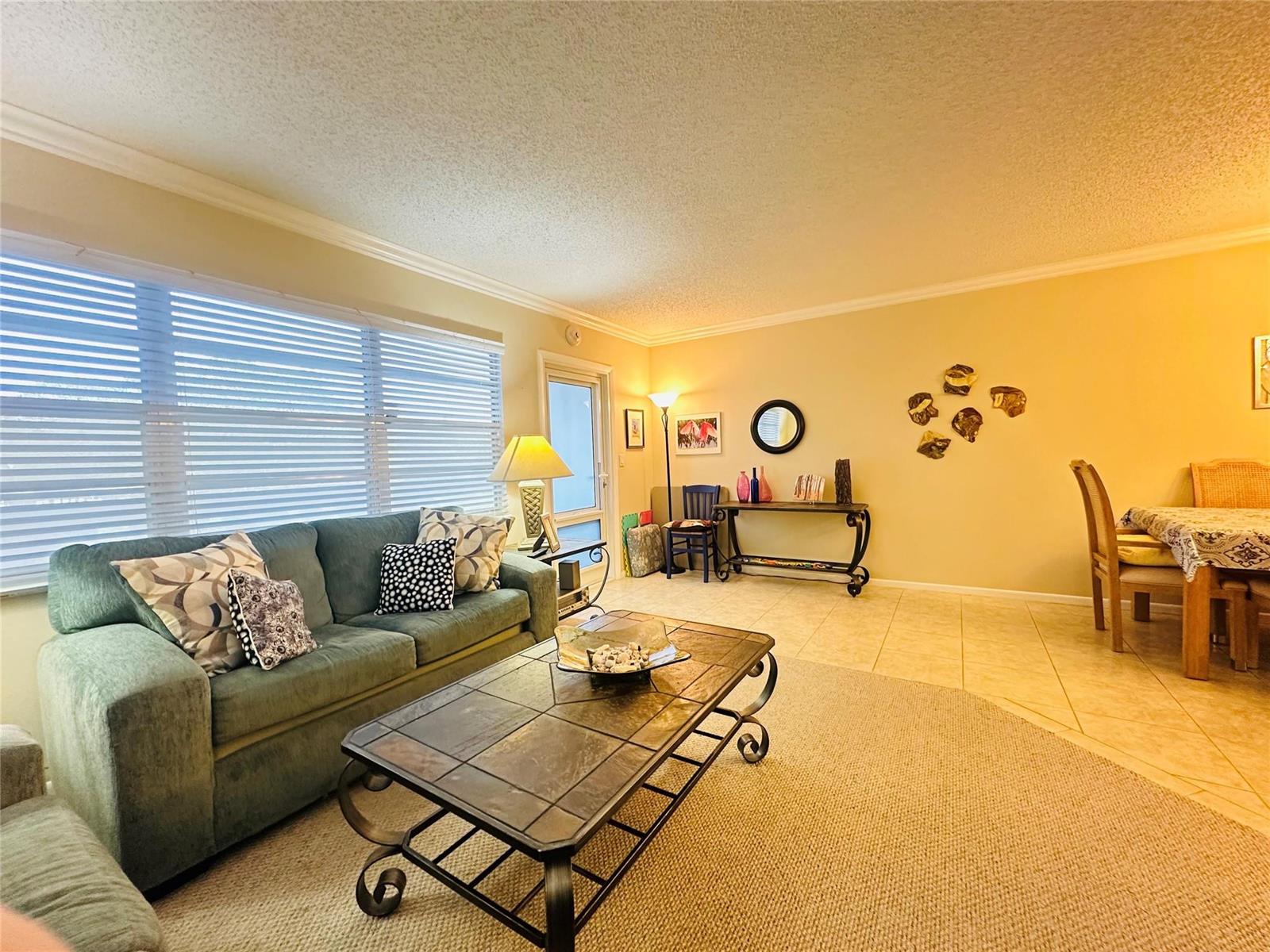 A living room features a teal sofa, a tiled coffee table, and a dining area — 2007 Islewood D # 2007, Deerfield Beach FL 33442, DEERFIELD BEACH, FL
