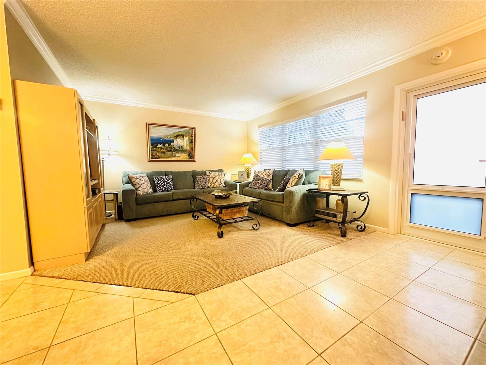A living room features two green sofas, a coffee table, and tile flooring — 2007 Islewood D # 2007, Deerfield Beach FL 33442, DEERFIELD BEACH, FL