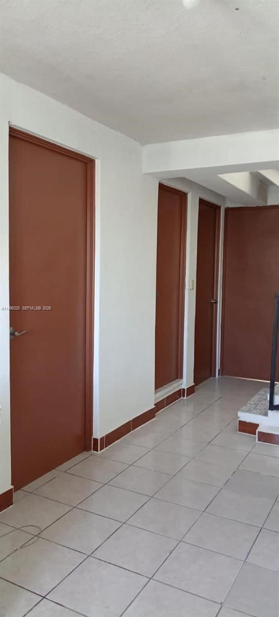 A hallway with white walls, tiled floors, and three brown doors — 9 Calle 8-92 Zona 11, MA 01057, MA