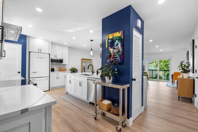A modern kitchen features white cabinets, stainless steel appliances, and a blue accent wall — 18460 SE Wood Haven Lane # H, Jupiter FL 33469, JUPITER, FL